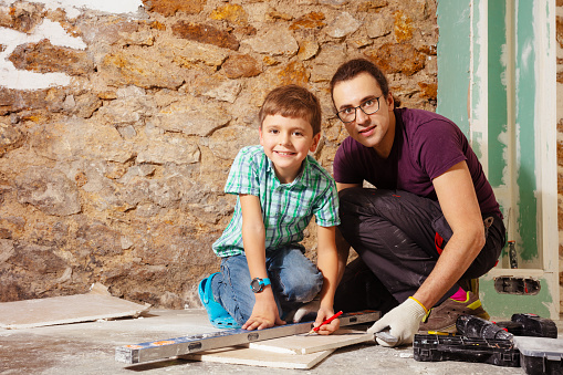 Father with son measure and cut plasterboard doing DIY home renovation together