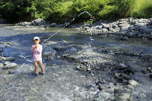 Japanese student girl playing in the river with water gun (7 years old)