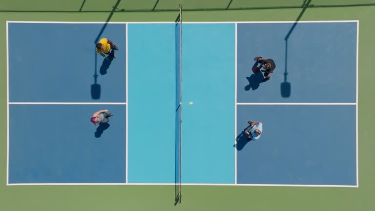 Top down drone shot of a group of people playing a doubles game of pickleball.