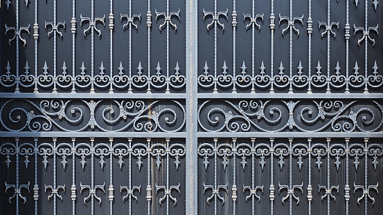 Forged patterned lattice with monograms and spades on massive gate. Biting business. production of iron decor. Reliable fortification of private territory