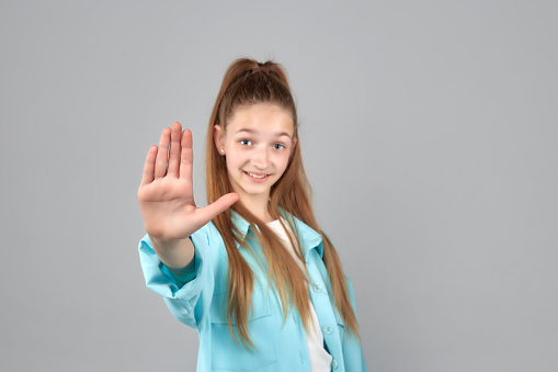 Close up studio portrait of 9 year old girl with long brown hair in gray dress on gray background