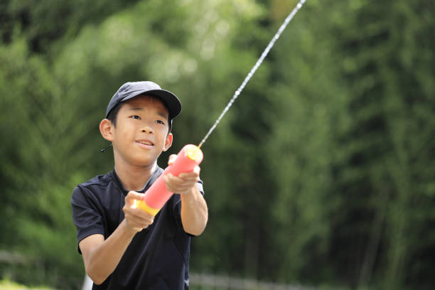 Japanese junior high school student playing in the river with water gun (12 years old boy)