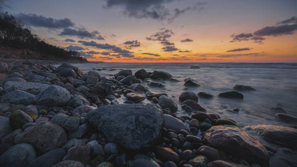 istock Colorful sunset on the sea rocky shore 1411727510