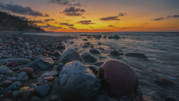 istock Colorful sunset on the sea rocky shore 1411727511