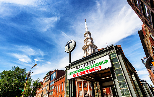 Boston, Massachusetts, USA - July 27, 2022: Street entrance to one of the Massachusetts Bay Transportation Authority's (MBTA) Park Street subway stations near the corner of Park and Tremont Street in downtown Boston. Park Street Church steeple in the background.