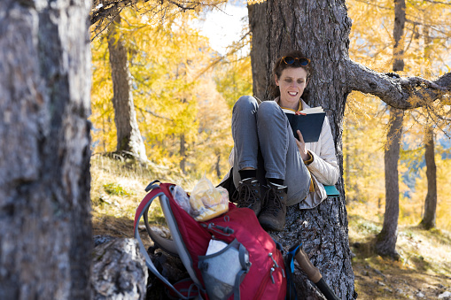 Serene Woman Hiker Taking a Break and Reading a Book on a Idyllic Tree