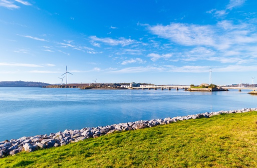 Expansive view across sea water to a bridge and windmills. With blue water and clear blue sky in Cork Ireland.