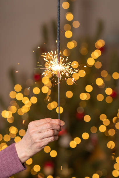 istock Sparkling beautiful sparkle or bengal lights against Christmas tree. Golden magic lights. Holiday , birthday or party concept. 1411739319