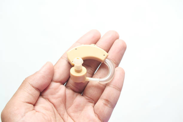 A small red hearing aid being held in a studio setting.