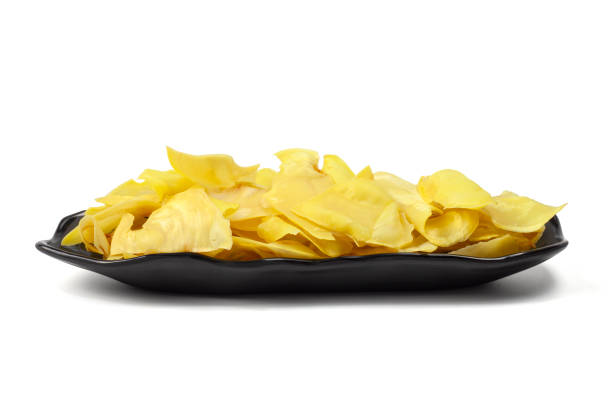 les chips de durian frites dans une assiette noire sont des snacks de thaïlande isolés sur fond blanc. - dried fruit variation healthy eating snack photos et images de collection