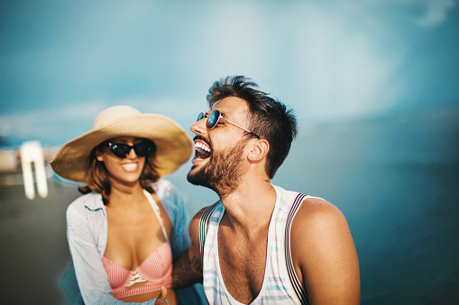 Young couple on the beach, laughing and enjoying every moment.