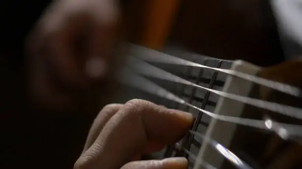 Close up of guitarist hand playing acoustic guitar. Close up shot of a man with his fingers on the frets of a guitar playing.