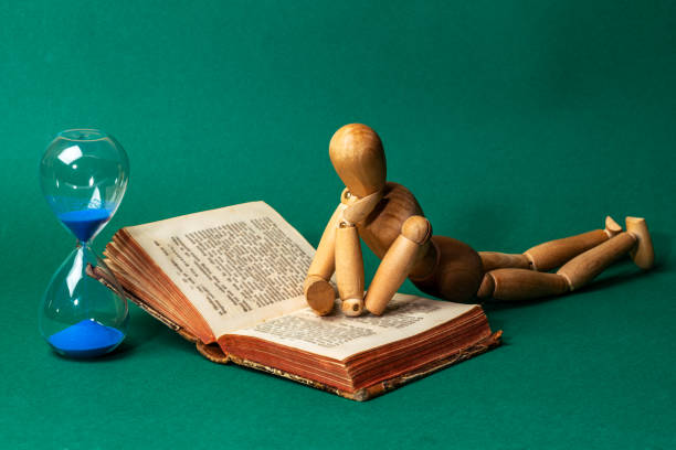 Wooden man lie down and rest on an open book. Education concept.