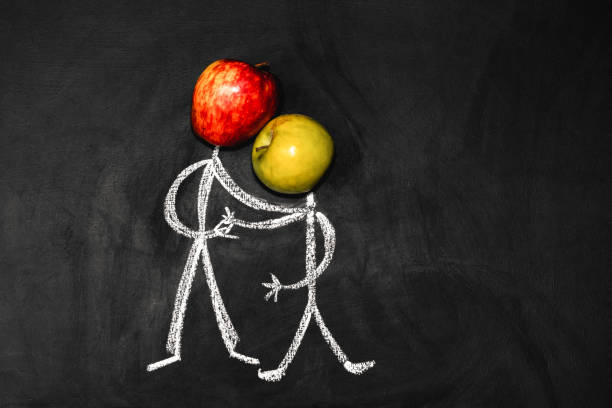 Two friends shake hands. Man with an apple instead of a head on a black background stock photo