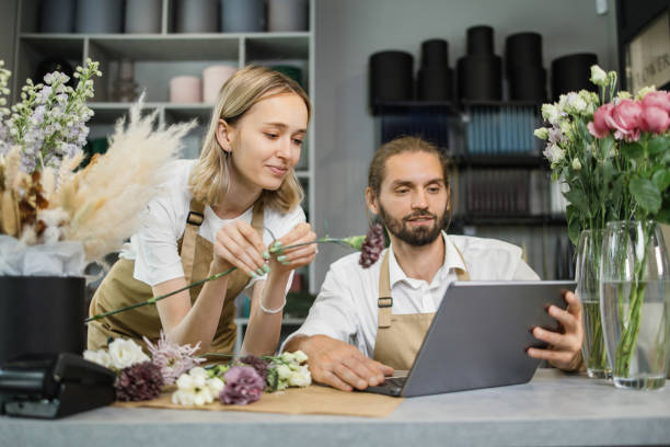 istock Two workers, man florist working on computer at workplace and woman helping him. 1411759645