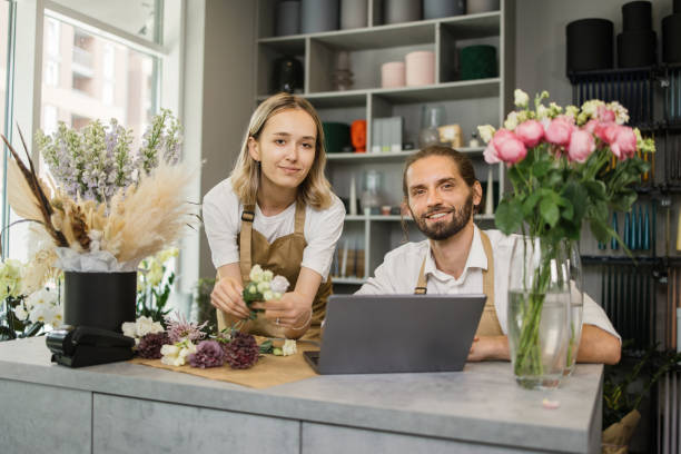 istock Two workers, man florist working on computer at workplace and woman helping him. 1411759646