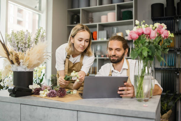 istock Two workers, man florist working on computer at workplace and woman helping him. 1411759647