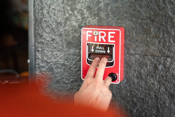 Activate fire alarm system. Activate fire alarm trigger system which is installed on granite wall of the building. Human action scene photo, selective focus. Notifier stock pictures, royalty-free photos & images