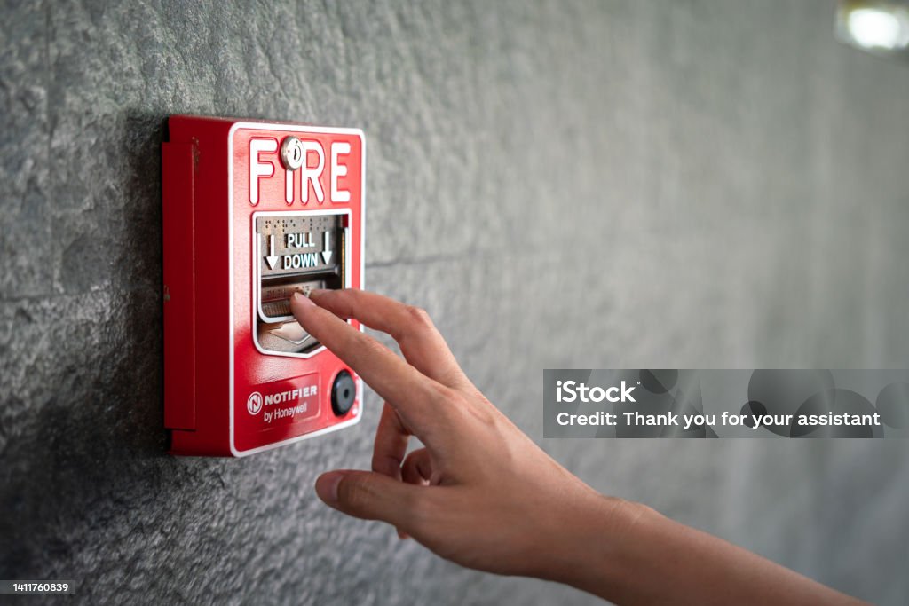 Activate fire alarm system. Activate fire alarm trigger system which is installed on granite wall of the building. Human action scene photo, selective focus. Fire Alarm Stock Photo