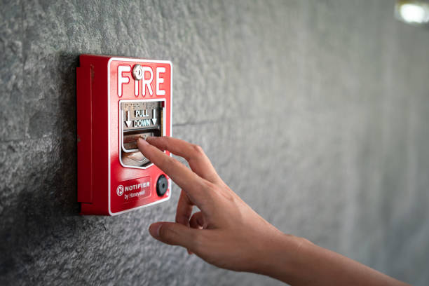 Activate fire alarm system. Activate fire alarm trigger system which is installed on granite wall of the building. Human action scene photo, selective focus. alarm stock pictures, royalty-free photos & images