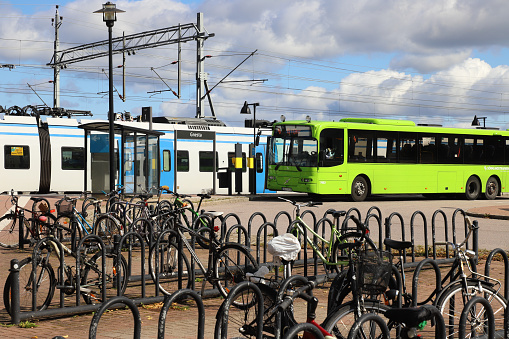 Gnesta, Sweden - September 3, 2021: Bikes in front of a green publc transport bus at the railroad station with a SL commuter train.