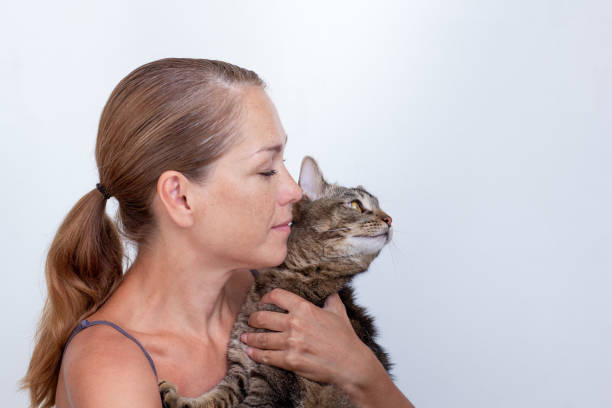 istock Woman hugging cat looking aside on white background 1411762849