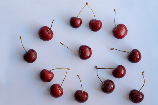 Cherries with a hard shadows randomly placed on a light background, hard light, top view