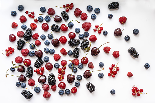 Red currant, raspberry, blueberry, blackberry scattered on a white background