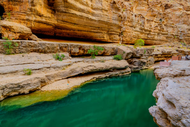 Wadi Al Shab , Sultanate of Oman. Wadi Al Shab Oman is characterized by its year-round flowing streams, as well as beautiful waterfalls and ever-flowing water riverbed stock pictures, royalty-free photos & images