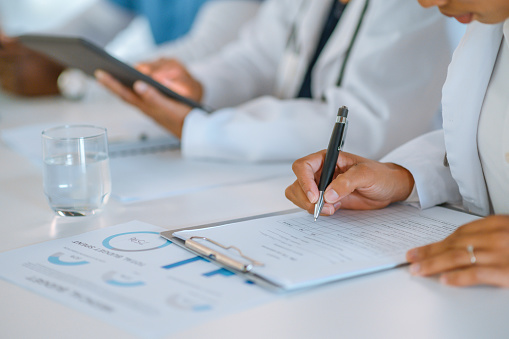 Hands of female doctor or businesswoman writing and checking boxes on a form or checklist during a medical conference. Healthcare worker or intern writing notes while attending a health seminar