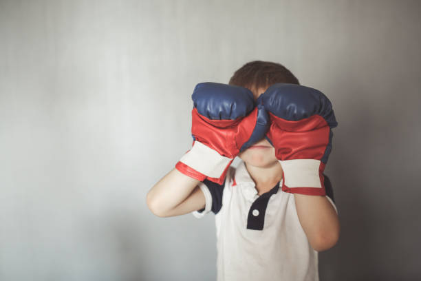 istock Kid boy in boxing gloves on neutral at home 1411771551