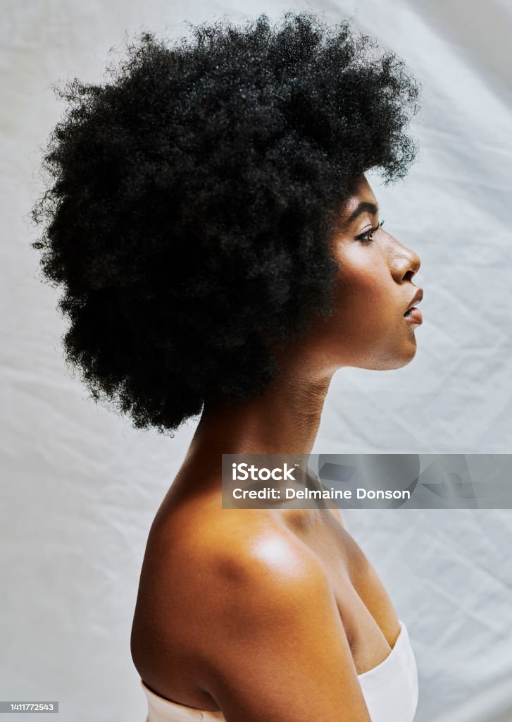 Side profile of african woman with afro isolated against a white background in a studio. Beautiful female with curly hair showing perfect skin for cosmetics and natural beauty for makeup products One Woman Only Stock Photo