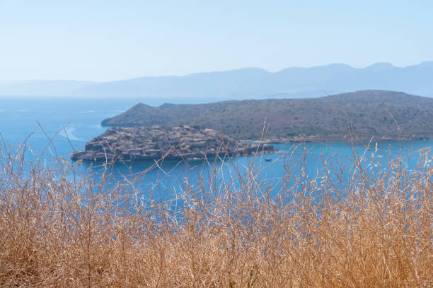 Hypnotic sea horizon with small islet Spinalonga, mountain hills and ship movement in blue water. Plaka, Crete island, Greece. Travel vacation concept.