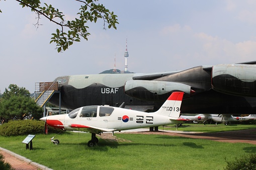 Seoul, Korea-July 26, 2022: Korean and U.S. Air Force planes displayed at the War Memorial of Korea, with Namsan (Seoul) Tower in the distance