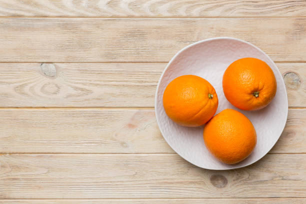 istock Flat lay of Fresh orange fruit with sliced in plate on Colored background. Top view with copy space 1411776101