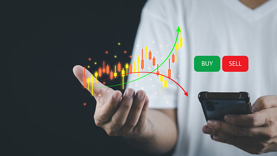 financial and investment technology concept men's hands are active Smartphone to plan stock chart analysis to invest in financial markets. The other hand has a virtual image as a candlestick chart.