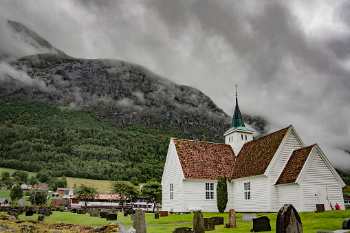 A church sits in the foreground of a mountain range in Olden Norway
