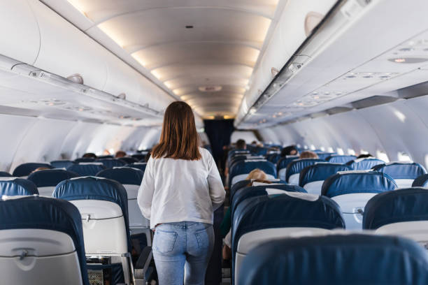 Girl leaving airplane's passenger cabin Rear view of a teenage girl walking on an airplane vehicle seat stock pictures, royalty-free photos & images
