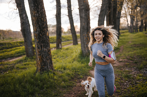 Young woman jogging with her dog in nature