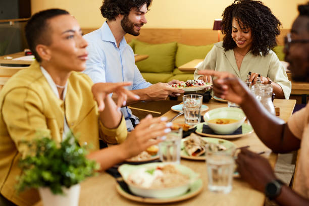 istock Group of multicultural friends sit in a restaurant, eating dinner an talking. 1411786430