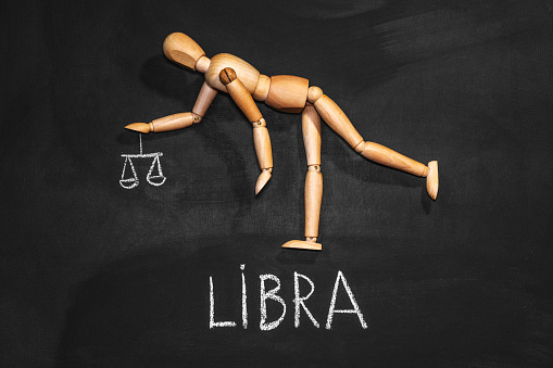 Wooden man depicts the zodiac sign Libra on a background of chalkboard