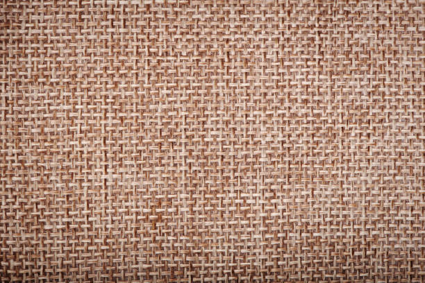 Burlap linen weave fabric background. Sackcloth material. Natural woven rustic bagging material. Light brown textile texture. Sacking linen fabric pattern. Closeup top view.