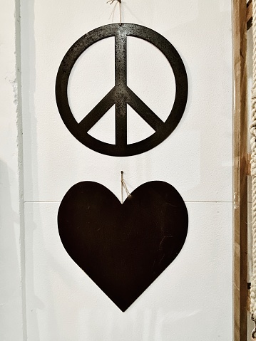 Vertical interior of metal cut out hanging symbols for peace & love heart on white wood wall
