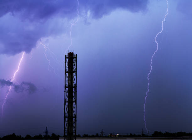 A branched lightning bolt crawls in dark night clouds. Thunder bolt over industrial zone. Thunderstorm in clouds.