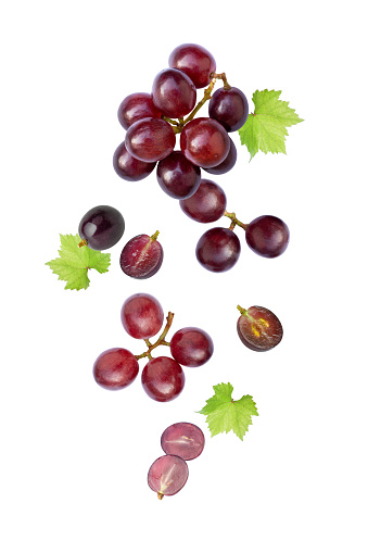 Red grape with leaves flying in the air isolated on white background.