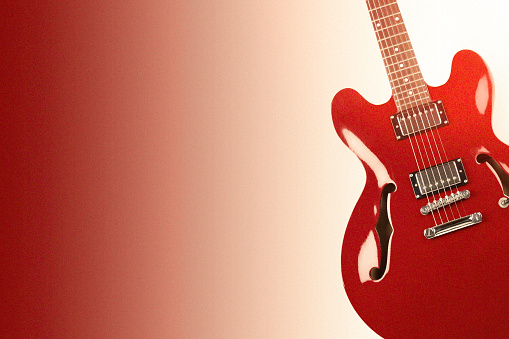 An electric guitar with red shiny body in dark environment and a lot of psace for additional content