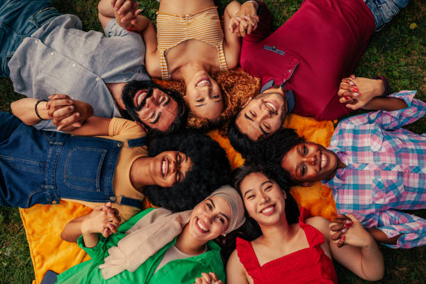 istock Group of friends lying on grass holding hands in circle 1411795746