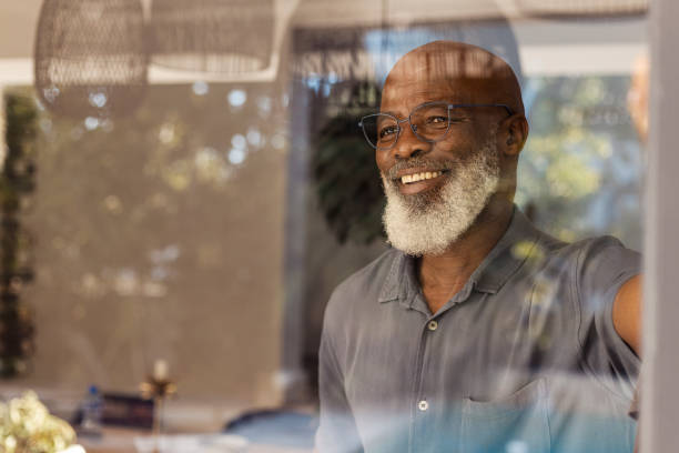 istock Handsome senior man looking out through his window 1411796191