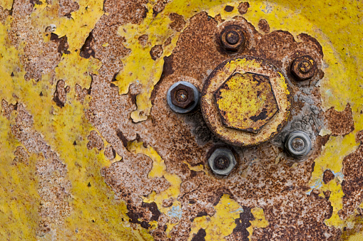 Rusty metal background with screws and traces of yellow paint.