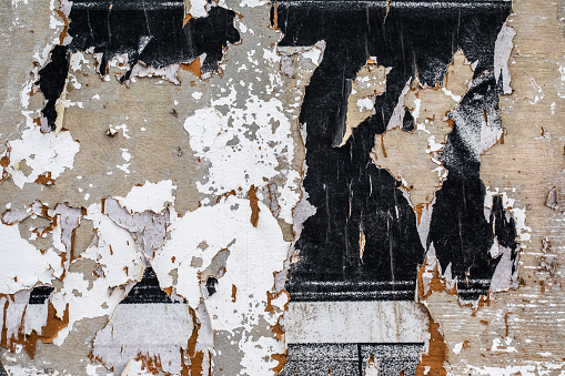 Close-up of a wall of torn pasted posters creates an urban background
